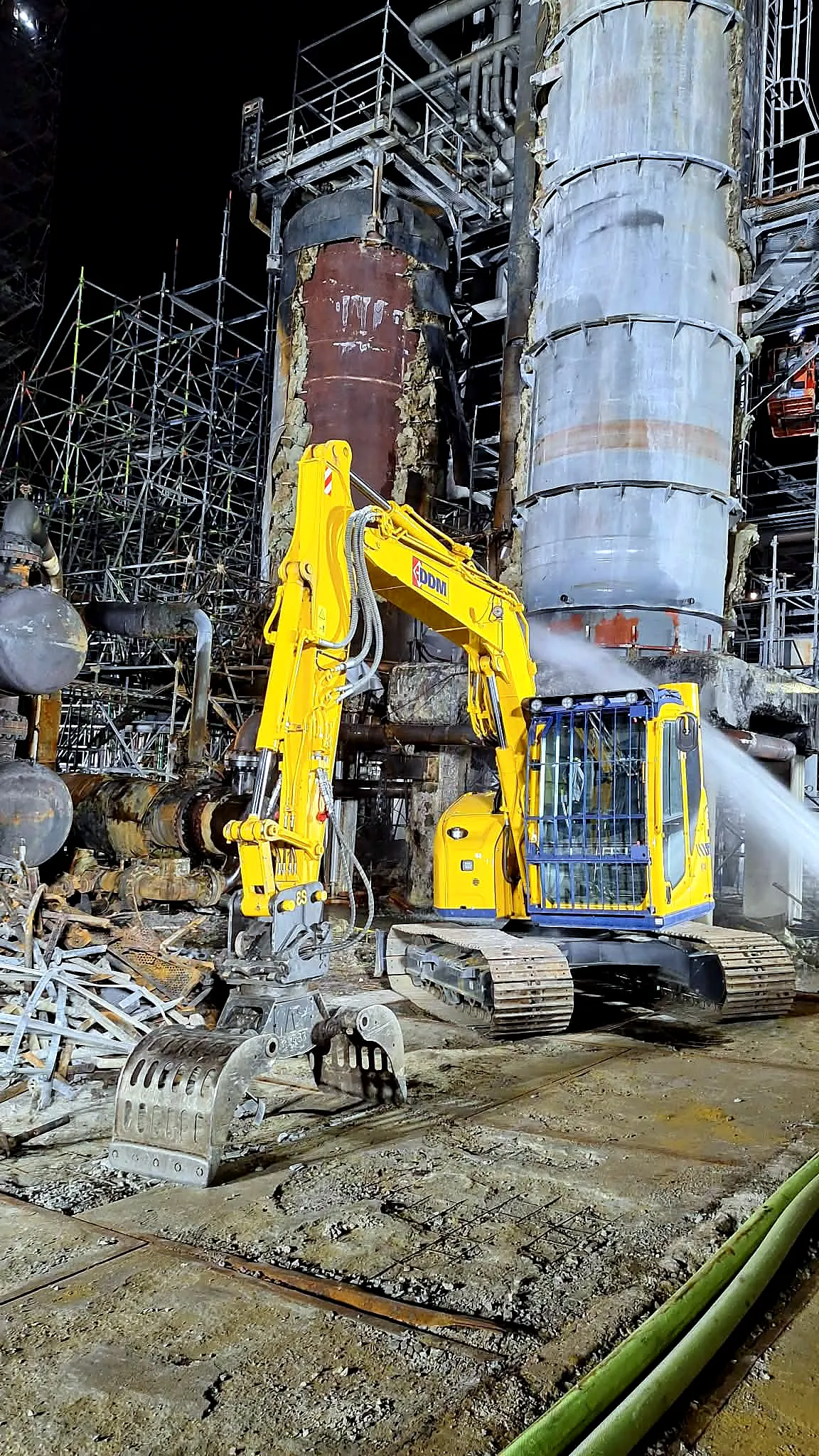 Nocna rozbiórka instalacji zakładu chemicznego, koparka i zraszanie